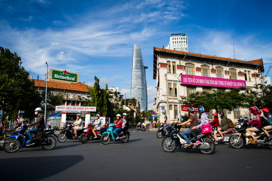 Scène de rue animée à Ho Chi Minh Ville avec scooters et tour Bitexco en arrière-plan